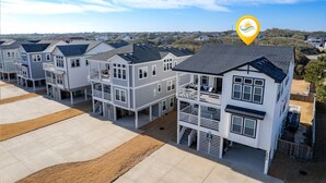 A row of modern, multi-story residential buildings with balconies and a clear view of the surrounding landscape. - Bikinis & Martinis: Walk Beach, Pool, Hot Tub (Kitty Hawk)