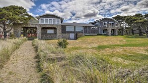 A two-story stone house with a stone archway entrance, a covered porch, and a large front lawn. - Coastal Oregon Retreat w/ Grill: 11 Mi to Astoria! (Warrenton)