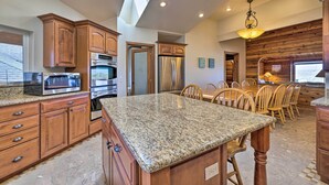 A kitchen with granite countertops, wooden cabinets, stainless steel appliances, and a dining area with wooden chairs. - Coastal Oregon Retreat w/ Grill: 11 Mi to Astoria! (Warrenton)