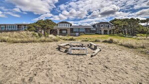 A beachfront property with a stone house, a fire pit, and a grassy area. - Coastal Oregon Retreat w/ Grill: 11 Mi to Astoria! (Warrenton)