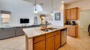 A modern kitchen with granite countertops, wooden cabinets, and a built-in dishwasher. - 5 Mi to Walt Disney World! Gem w/ Resort Perks (Kissimmee)