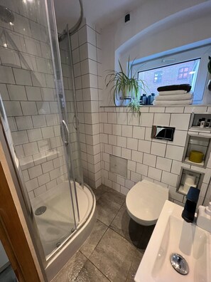 Een douche, handdoeken, zeep, toiletpapier