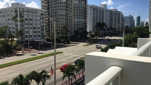A city street with tall buildings, a red car, and palm trees. - Pavilion by Design Suites Miami (Miami Beach)