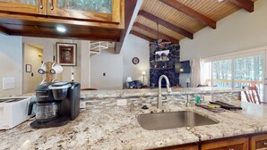 A kitchen with a stone backsplash, granite countertop, and a built-in sink. - Pet Friendly | Close to Lifts | Spacious | Garage Access | Angel Fire Commons C8 (Angel Fire)