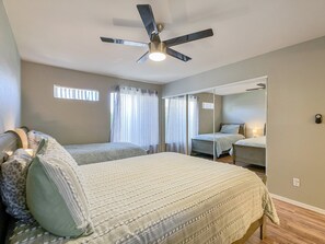 A bedroom with two beds, a ceiling fan, a large mirror, and a window with curtains. - Sunscape Unwind - resort community! (Scottsdale)