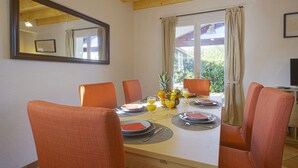 A dining area with a wooden table, orange chairs, and a window with curtains.