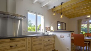A modern kitchen with wooden cabinets, a stainless steel range hood, and a large window providing natural light.