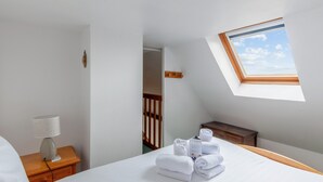 A bedroom with a skylight, a bedside table with a lamp, and neatly folded towels on the bed. - Appartement Sémaphore - Welkeys (Cabourg)