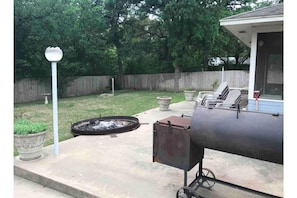 Relax in a backyard oasis with a barbecue grill and fire pit, perfect for al fresco dining and cozy gatherings.