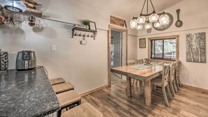 Une cuisine moderne dotée d’un plan de travail en granit, d’un four encastré et d’un coin repas avec une table et des chaises en bois.