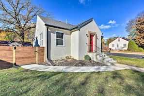 A single-story house with a red door, a small front yard, and a wooden fence.
