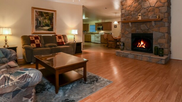 Una sala de estar con chimenea de piedra, piso de madera y comedor con mesa y sillas.