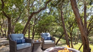 An outdoor seating area with wicker chairs and a fire pit. - Renovated w/ Pool, Golf, Games & Backyard Activities! (Dripping Springs)