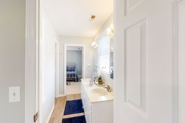 Enter a serene bathroom area with a white sink, mirror, and towel rack.