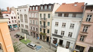 A street view with a restaurant named "RESTAURACJA" on the right, a parked car, and a bicycle. - Bonjour Apartment - Old Town Mostowa  - Central Location (Toruń)