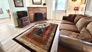 A living room with a fireplace, a sofa, a coffee table, and a television.