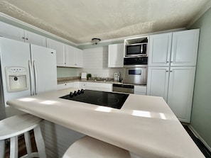A modern kitchen with white cabinets, a black stove, and stainless steel appliances. - Cute, Cozy Home! Only ONE Block From Mercy! (Springfield)