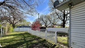 A residential property with a white picket fence, a garage, and a lawn.