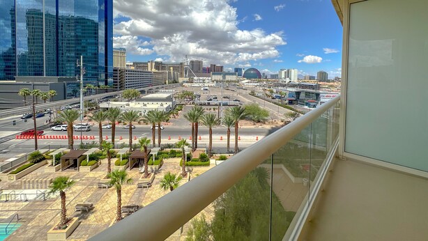 A cityscape with modern buildings, a parking area, and palm trees. - MGM Signature Balcony Suite 5073 NO RESORT FEE (Las Vegas)