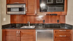A kitchen with wooden cabinets, a stainless steel microwave, a built-in oven, a sink, and a dishwasher. - MGM Signature Balcony Suite 5073 NO RESORT FEE (Las Vegas)