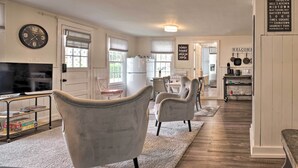 A modern kitchen with a refrigerator, stove, and dining area. There is a clock on the wall and a sign with a welcome message. - Romantic Country Apt by Lake Erie & Wineries! (Westfield)