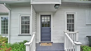 A house with a front porch, a dark blue door, and a white railing. - Romantic Country Apt by Lake Erie & Wineries! (Westfield)