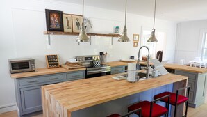 Een moderne keuken met een centraal eiland, barstoelen, hanglampen en een inbouwoven.
