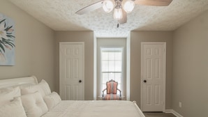 A bedroom with a large bed, a ceiling fan, and a window with blinds. - Welcoming Woodmere Wonder, WiFi, Pool & Parking (Montgomery)
