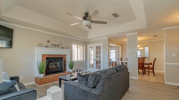 A living room with a fireplace, a sofa, a dining area with a table and chairs, and a ceiling fan. - Welcoming Woodmere Wonder, WiFi, Pool & Parking (Montgomery)