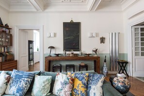 A living room with a sofa, a fireplace, a bookshelf, and a dining table.