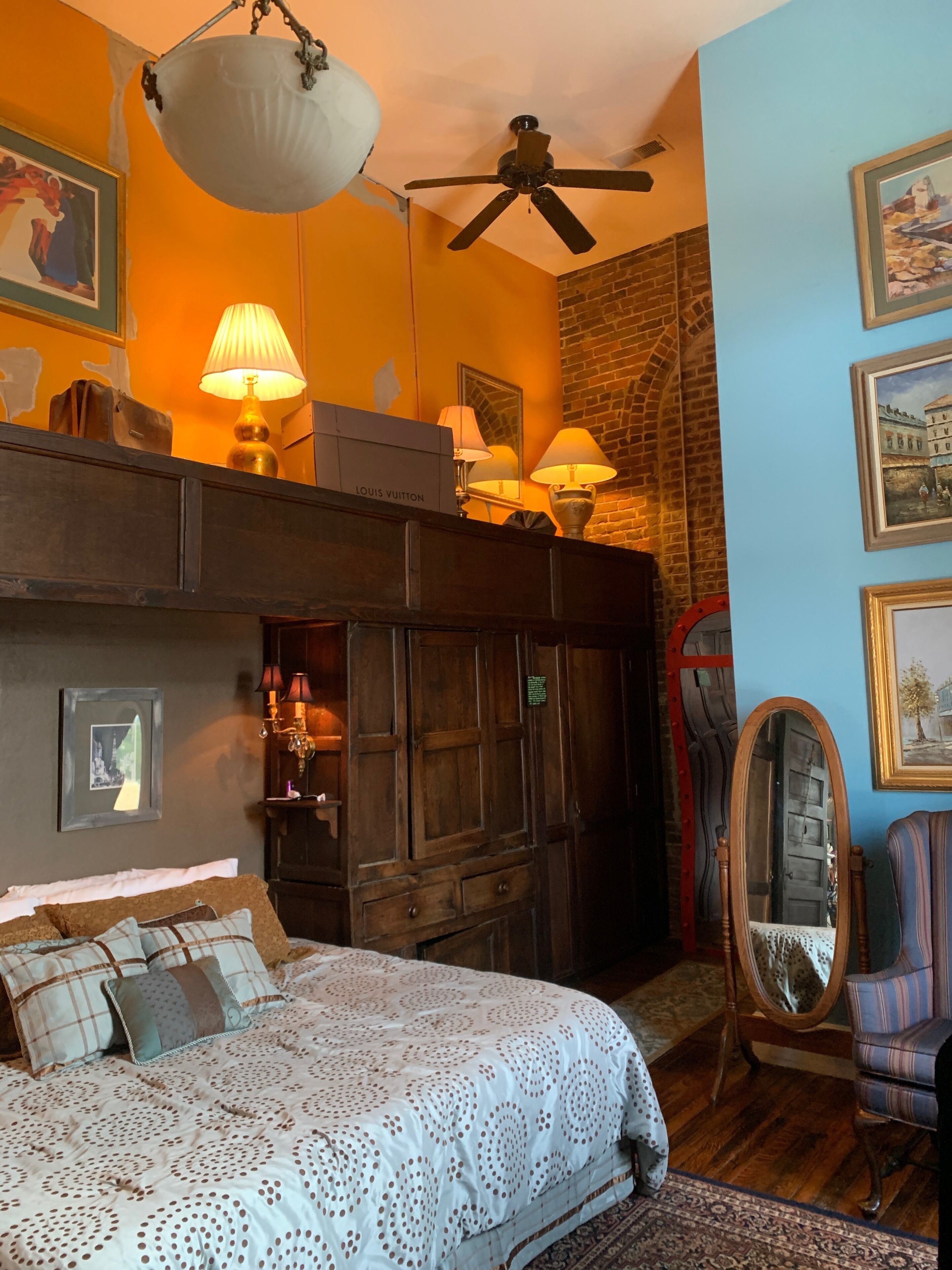 A bedroom with a large bed, a wardrobe, a mirror, and a ceiling fan.