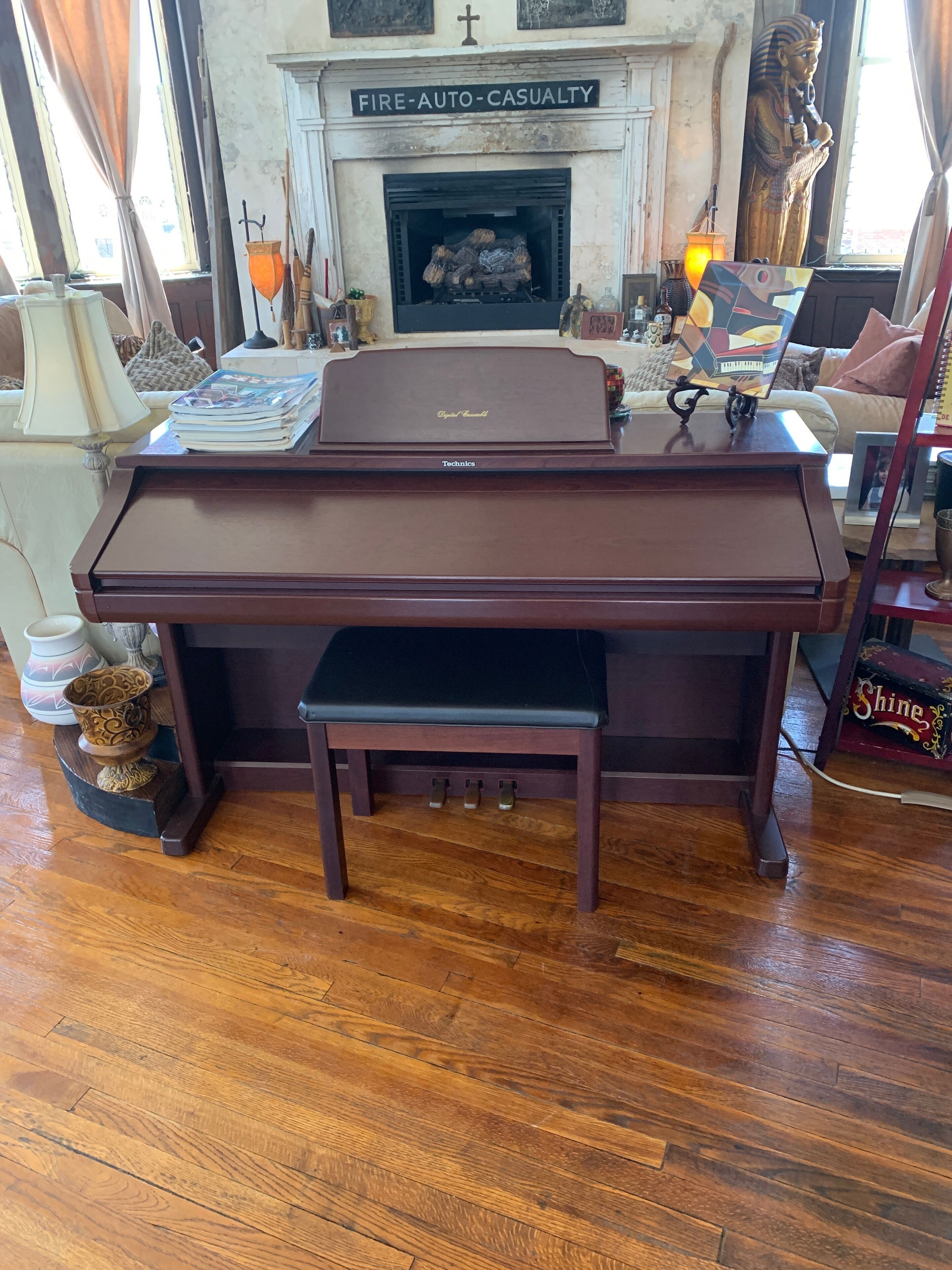 Um piano de cauda em um aposento com lareira, piso de madeira e diversos objetos decorativos.