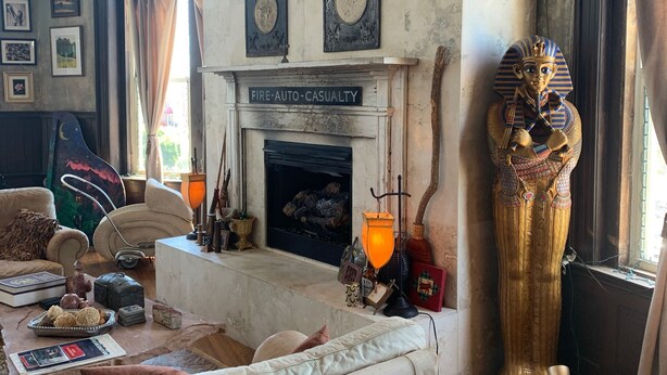 Una habitación con chimenea, una estatua grande y varios objetos decorativos.
