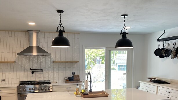 A modern kitchen with a large island, wooden stools, stainless steel appliances, and pendant lighting. - Hampton Bays Family Summer Home (Hampton bays)