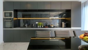 A modern kitchen with dark cabinetry, a built-in oven, and a sleek black island. - Dots n' Stripes by Interhome (Fažana)