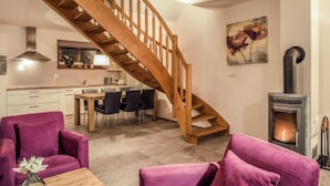 Una sala de estar moderna con escalera de madera, comedor y chimenea.