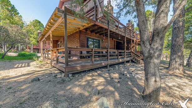 Eine rustikale Holzhütte mit einer Holzdiele, umgeben von Bäumen und einem klaren Himmel.