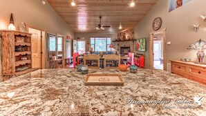 A spacious living area with a large marble floor, wooden ceiling, and a central seating area with a table and chairs. - Spotted Owl Pet Friendly | Your Peaceful Pine Retreat w/ Owl-Worthy Views & Hot Tub Soaks (Ruidoso)