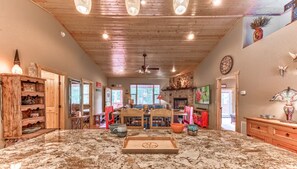 A spacious living area with a large marble floor, wooden ceiling, and a central seating area with a table and chairs.