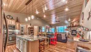 A spacious kitchen with wooden cabinets, a central island, and a dining area with a red chair.