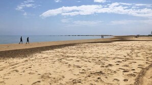 Een zandstrand met voetafdrukken en een heldere lucht.