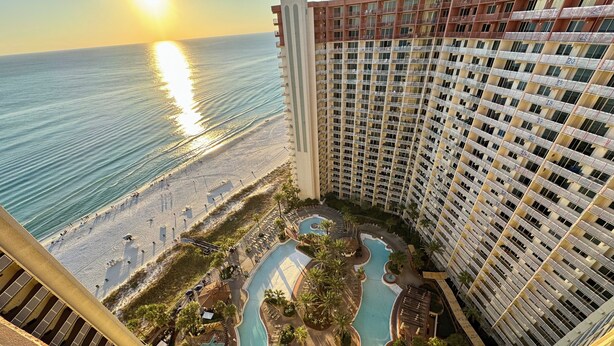 Un hotel de gran altura con zona de piscina, playa y vistas al atardecer.