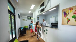 Una zona de recepción con mostrador, un espacio de estar con sofá y sillones, y un mapa mundial en la pared.