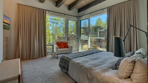 Ein Schlafzimmer mit einem großen Bett, einem Sessel, einem Schreibtisch und einem fensterbepflanzten Fenster.