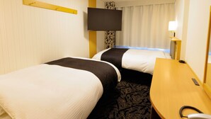 Une chambre d’hôtel avec deux lits, un bureau, une chaise, un téléviseur à écran plat et une lampe de chevet.