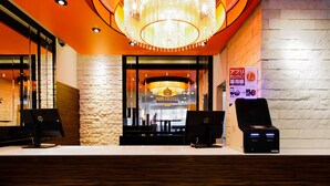 Un comptoir d’accueil d’hôtel avec deux ordinateurs HP, un lustre et un mur en pierre.