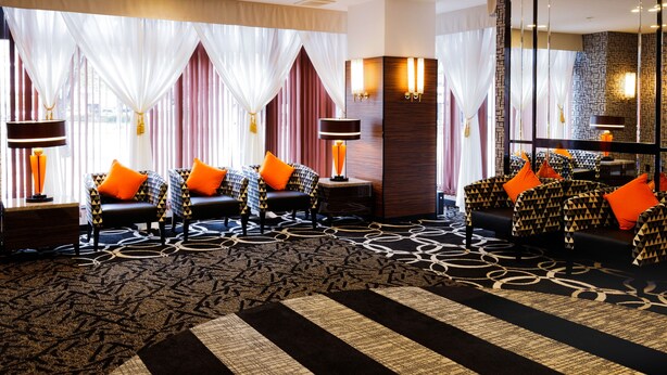 Un hall d’hôtel avec des canapés à motifs, une moquette à motifs et un grand miroir qui reflète la pièce.