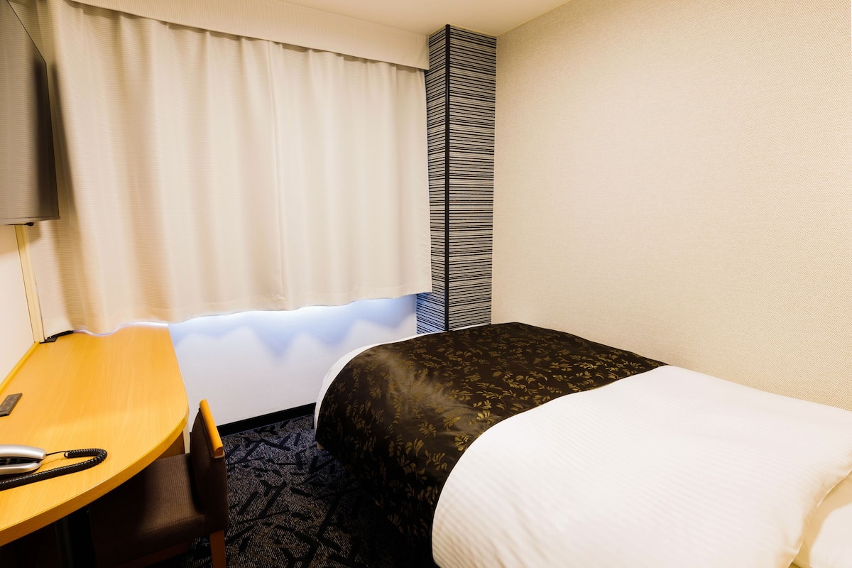 Une chambre d’hôtel avec un lit, un bureau et une chaise.