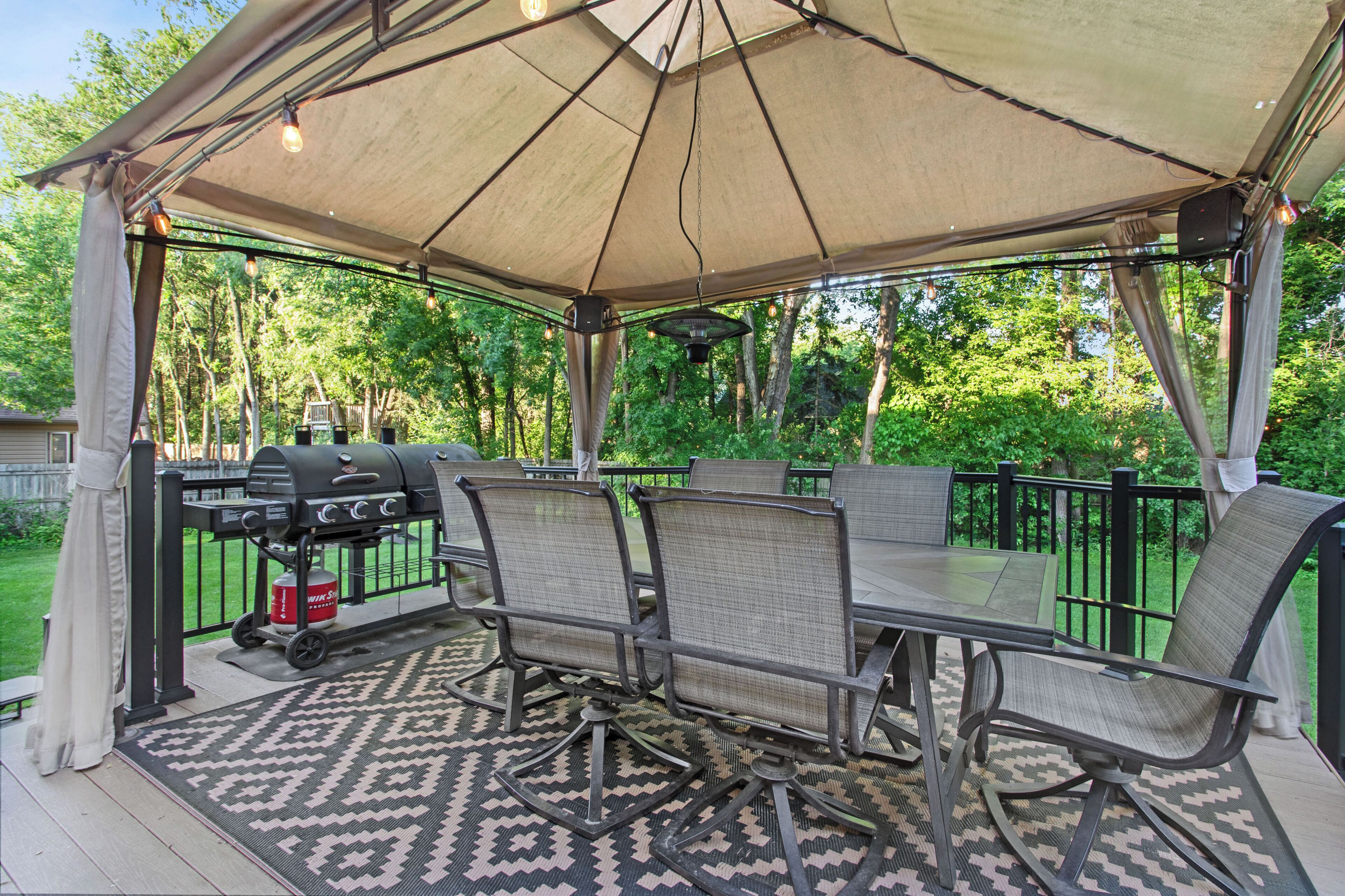 Un patio al aire libre con mesa y sillas, una parrilla y un toldo.