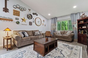 Ein Wohnzimmer mit zwei Sofas, einem Couchtisch und einem Bücherregal.
